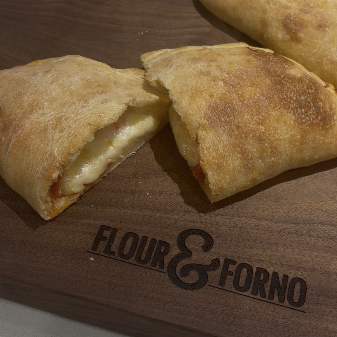 Cheesy calzones on a branded peel